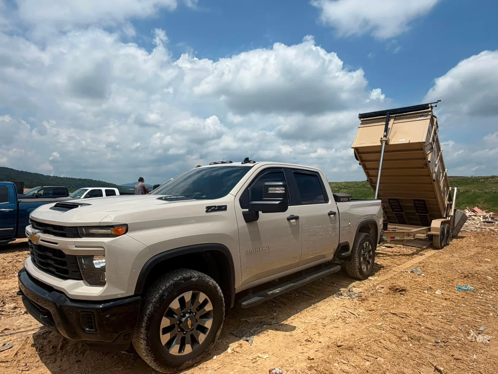 A white pickup beside a raised dump trailer